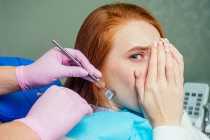 una mujer con ansiedad dental mientras le intentan hacer una intervención en el dentista