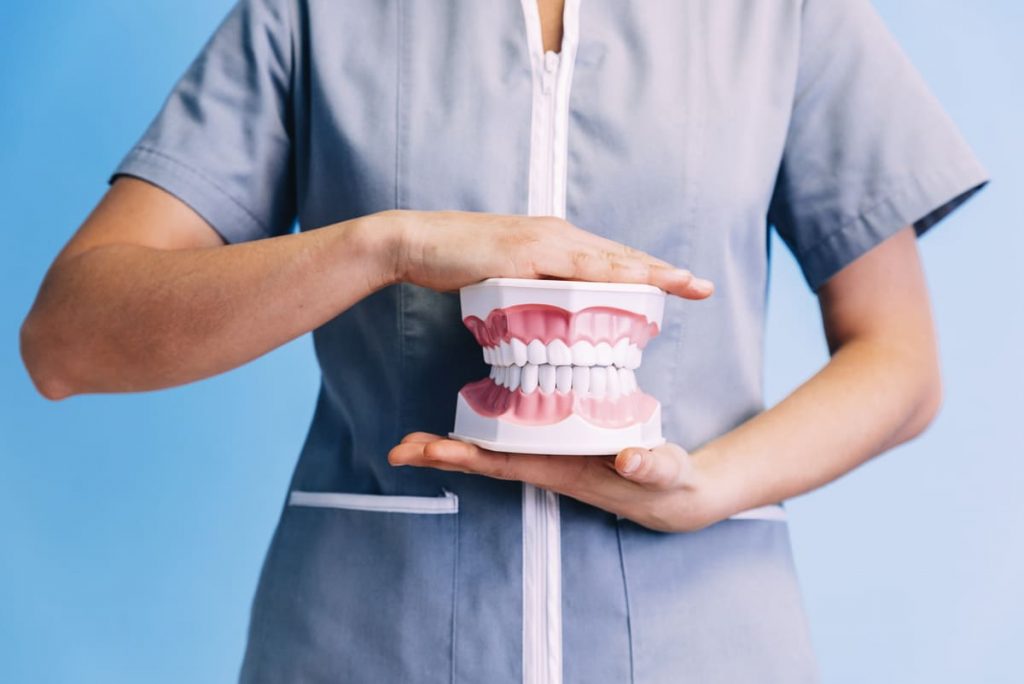 mujer sosteniendo un modelo de dentadura simbolizando los tratamientos dentales con sedación consciente